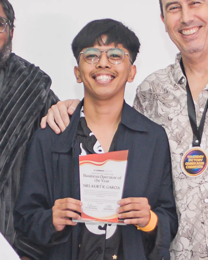 Niel Kurt Garcia smiling on stage, holding his Business Operator of the Year award.